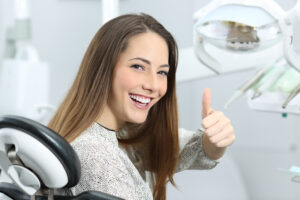 Patient with perfect white teeth and smile satisfied after dental treatment in a dentist office with medical equipment in the background