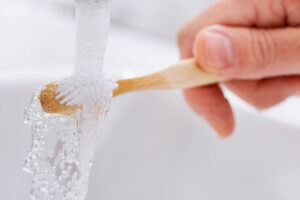 closeup of a caucasian man using a bamboo toothbrush in the bathroom