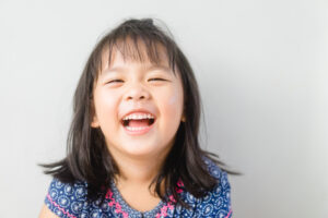 Happy Little asian girl child showing front teeth with big smile
