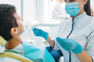Smiling little boy in a dental chair, professional pediatric dentistry, children stomatology, female dentist on background
